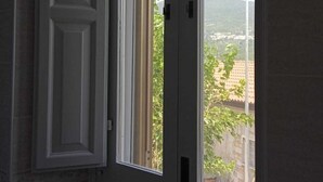 A room with a large window, a door, and a small window with a view of greenery and buildings outside. - I 3 falchi Bed & Breakfast (Pennadomo)