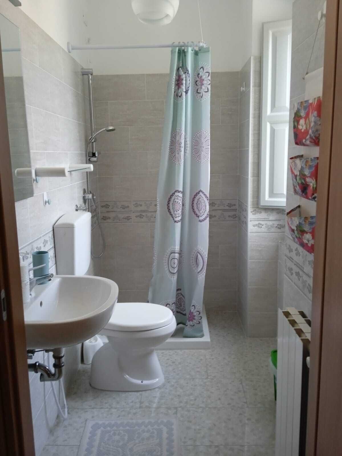 Un baño pequeño con inodoro, lavamanos, ducha y ventana.