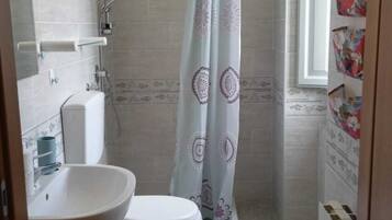 Un baño pequeño con inodoro, lavamanos, ducha y ventana.