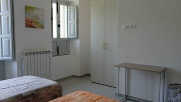 Ein Zimmer mit einem Bett, einem Tisch, einem Schrank, einer Heizung und einem Bild an der Wand.