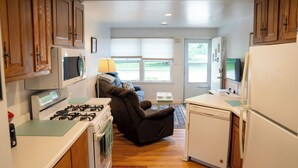 A compact kitchen with wooden cabinets, a gas stove, a microwave, a refrigerator, and a built-in seating area. - Viola Suite #2 | Quiet 2BR, Lg Yard, 3 Mi to Mayo! (Rochester)