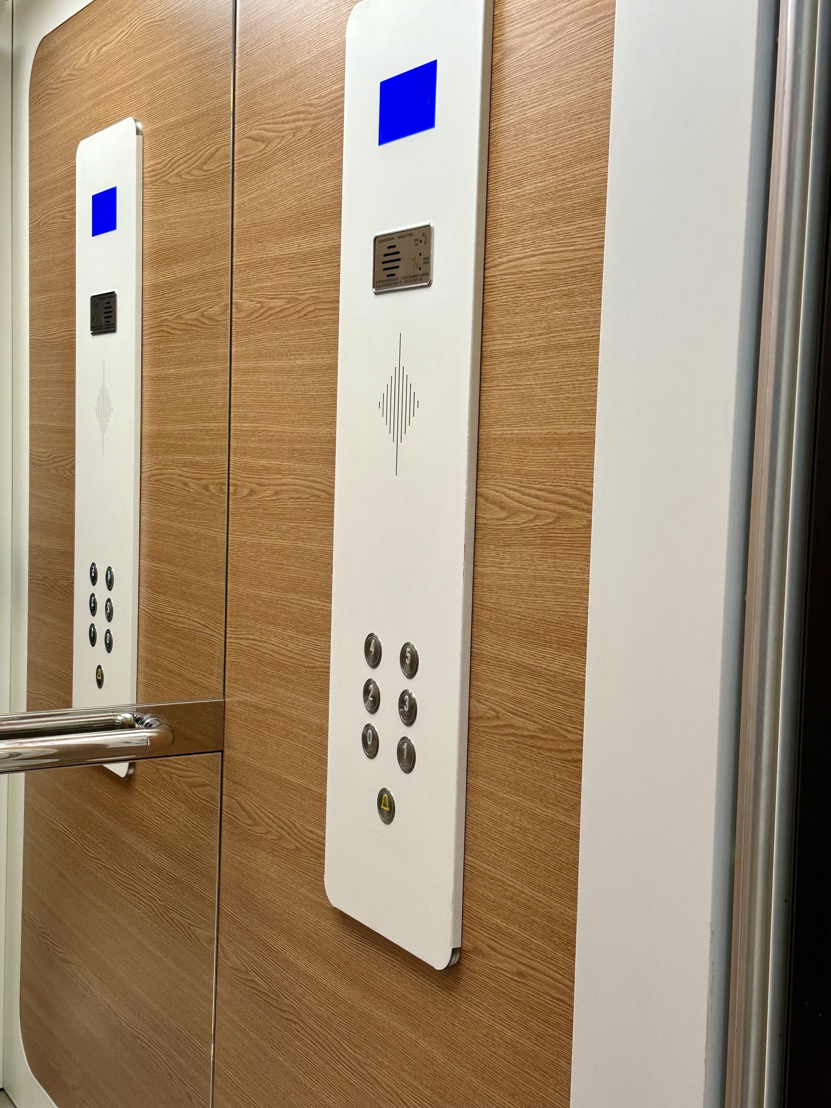 An elevator control panel with a keypad, a blue square button, and a speaker grille.
