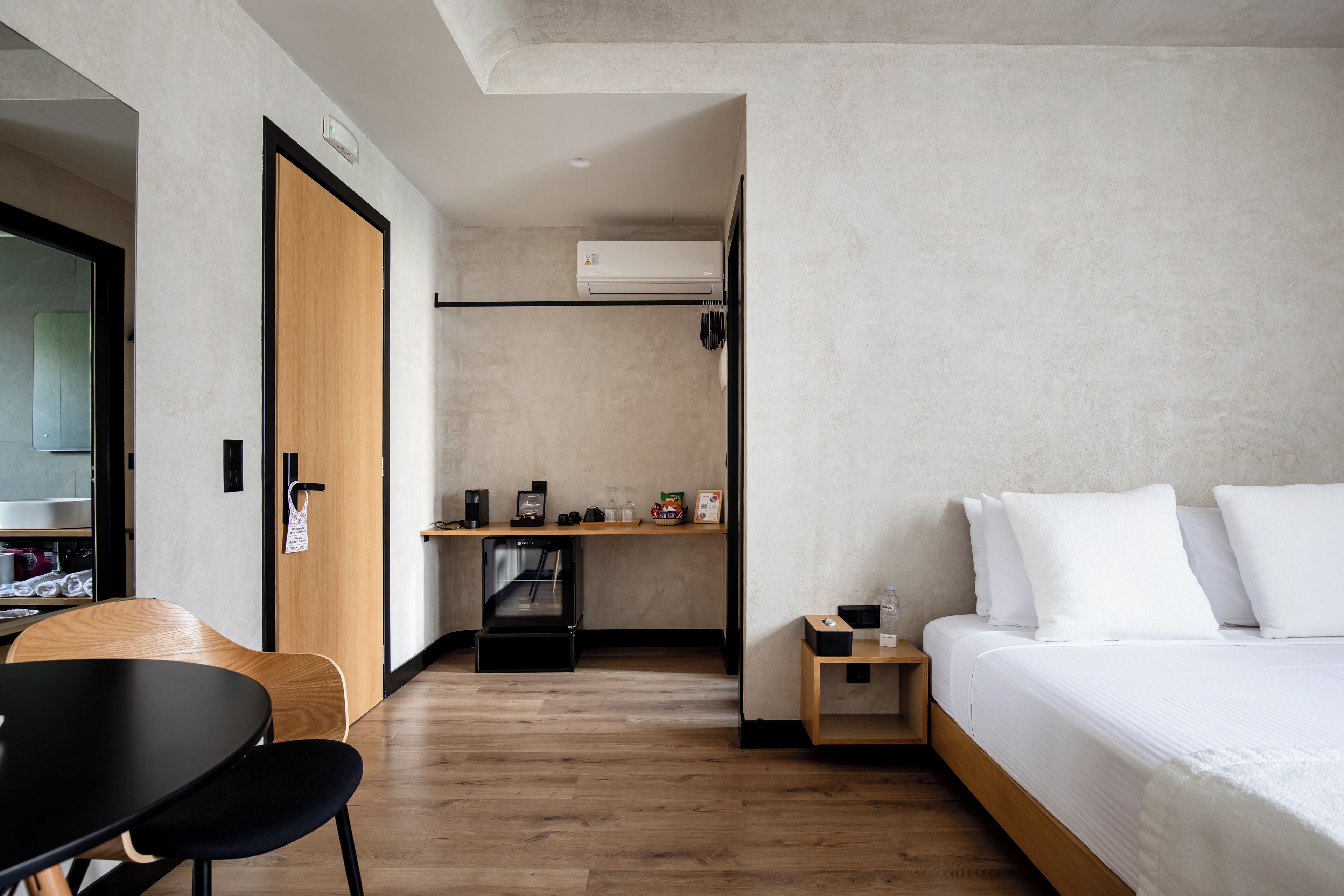 Una habitación de hotel con una cama, un escritorio con una cafetera, una silla y un armario.