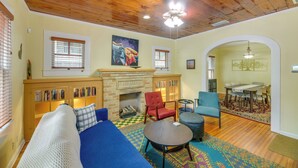 A cozy living room with a fireplace, a blue sofa, a red armchair, and a dining area in the background. - San Antonio Gem in Prime Location w/ Outdoor Space (San Antonio)