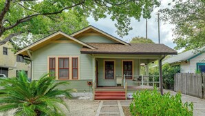 A two-story house with a front porch, a small garden, and a pathway leading to the entrance. - San Antonio Gem in Prime Location w/ Outdoor Space (San Antonio)