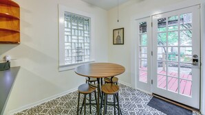 A room with a round table and four stools, a ceiling fan, a window with a view of a red deck, and a door with a glass panel. - San Antonio Gem in Prime Location w/ Outdoor Space (San Antonio)