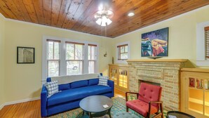 A living room with a blue sofa, a red armchair, a round coffee table, and a fireplace. - San Antonio Gem in Prime Location w/ Outdoor Space (San Antonio)