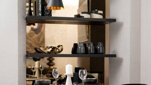 Un comedor moderno con una mesa redonda, sillas negras y una base cónica original.