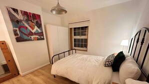 A bedroom with a bed, a window, a painting, and a wardrobe. - Essex 2-bed House nr Stanstead With Arcade Machine (Braintree)
