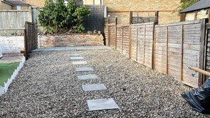 A gravel pathway with stepping stones leading to a wooden fence. - Essex 2-bed House nr Stanstead With Arcade Machine (Braintree)
