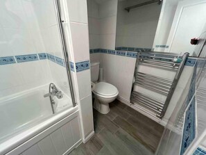 A bathroom with a bathtub, toilet, and a towel rack. - Essex 2-bed House nr Stanstead With Arcade Machine (Braintree)