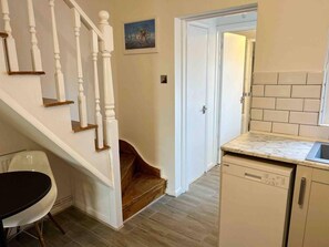 A kitchen with white cabinets, a marble countertop, and a dishwasher. - Essex 2-bed House nr Stanstead With Arcade Machine (Braintree)