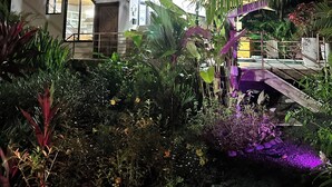 A modern two-story house with large windows and a balcony, surrounded by lush tropical plants and a small bridge. - BEACHFRONTGEM- owner’s villa-expansive endless beach. Amazing Sept Oct discounts (Savegre)