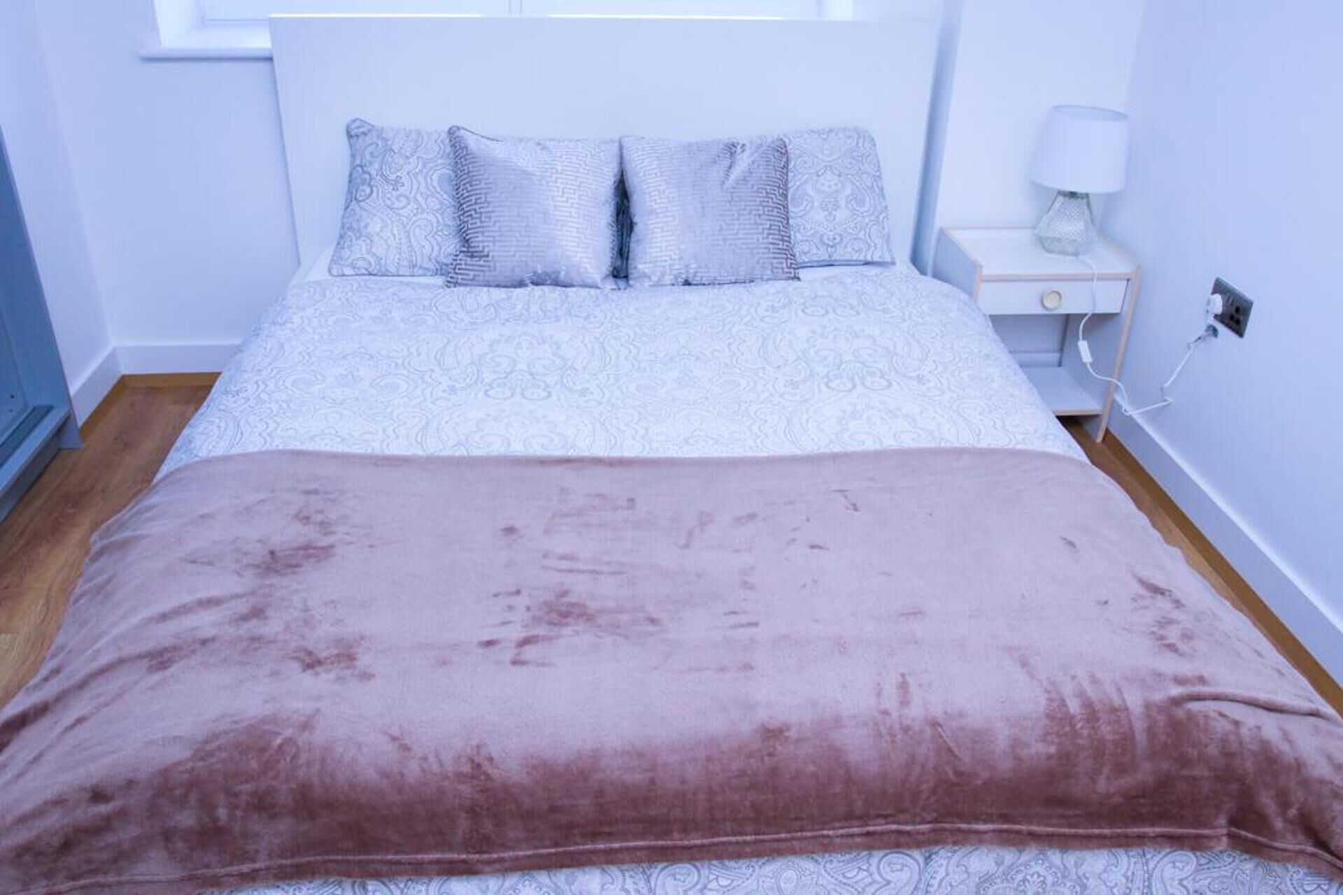 Une chambre à coucher avec un lit, une table de chevet et une lampe.