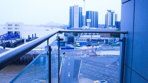 A view from a balcony overlooking a cityscape with a river, modern buildings, and a construction crane. - Thout Seaview Luxury Apartment (London)