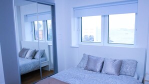 A bedroom with a bed, a mirror, and a window. - Thout Seaview Luxury Apartment (London)