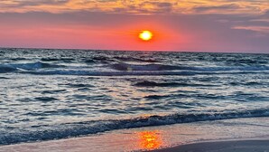 Ein Sonnenuntergang über dem Meer, Wellen nähern sich dem Strand.