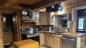 Een moderne keuken met houten kasten, roestvrijstalen apparatuur en een houten eettafel.