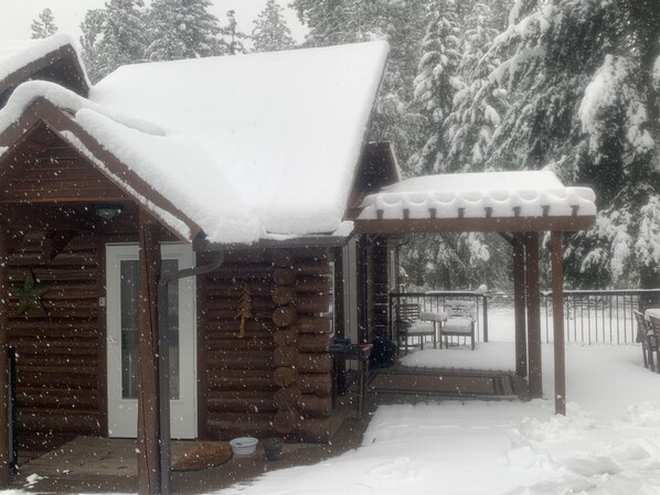 Eine Blockhütte mit verschneietem Dach und einer Veranda.