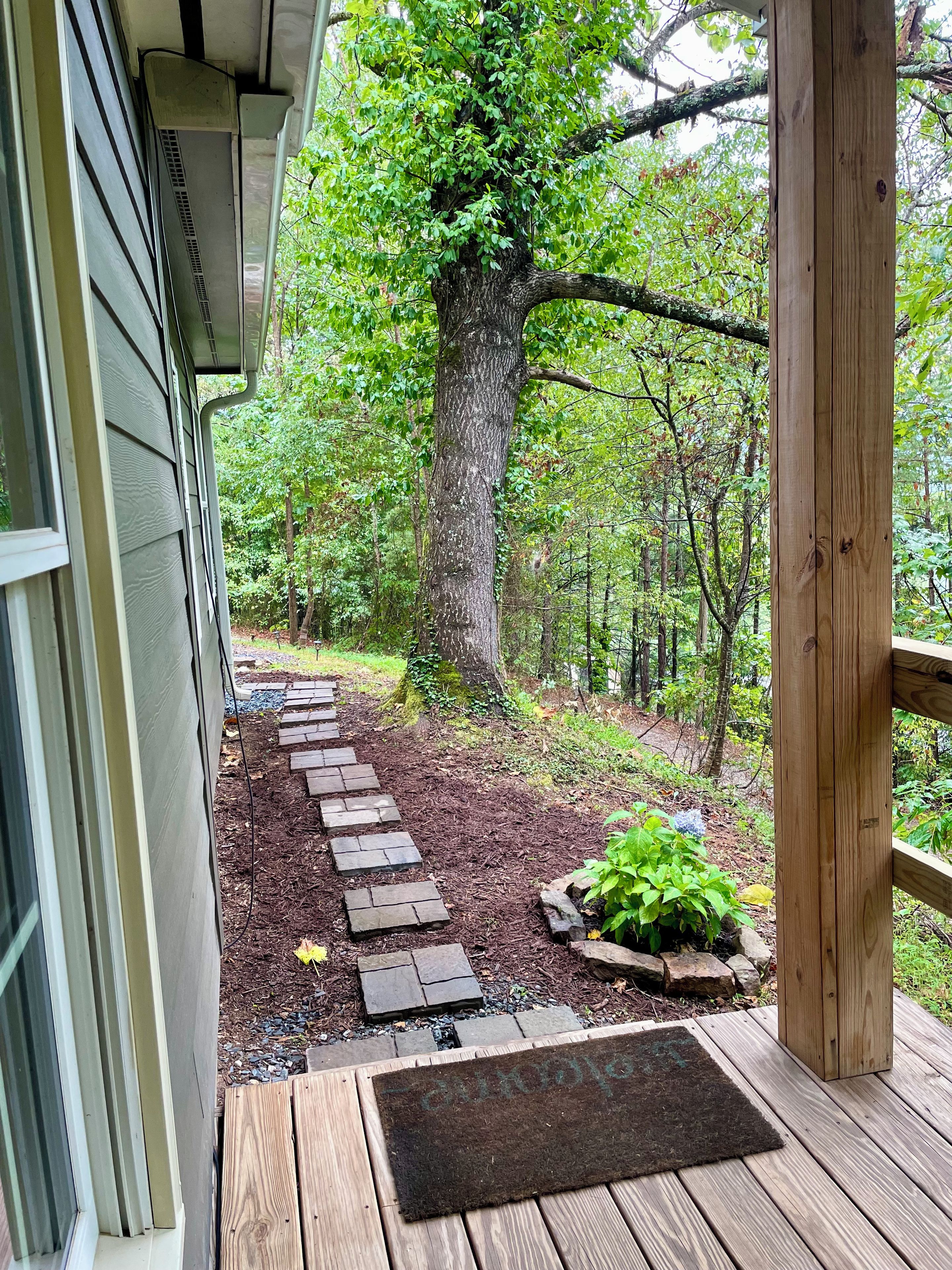 Une terrasse en bois menant à une maison qui offre une vue sur une forêt.
