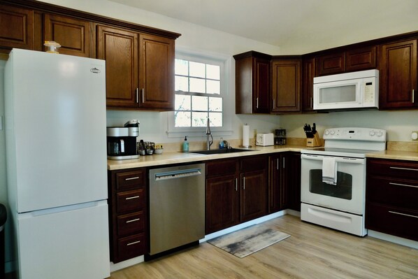 A kitchen with wooden cabinets, a white refrigerator, a dishwasher, a microwave, and an oven.