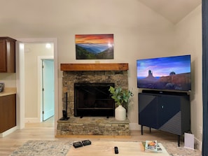 Ein Wohnzimmer mit Kamin aus Stein, einem Flachbildfernseher und einer Fernbedienung auf dem Boden.