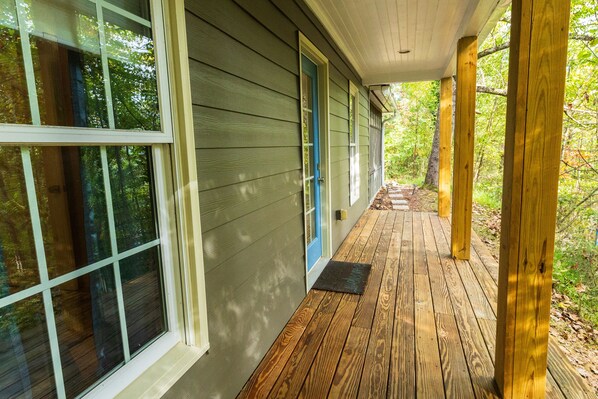 A wooden deck with a covered porch, large windows, and a door.