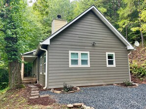 A single-story house with a front porch, a chimney, and a satellite dish.