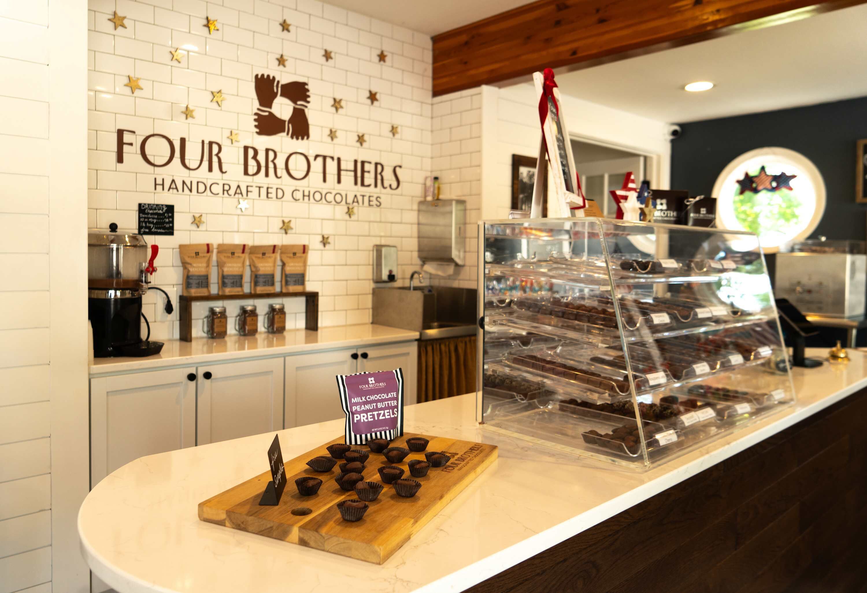 Eine Theke einer Bäckerei mit einem Schild, auf dem 'FOUR BROTHERS HANDCRAFTED CHOCOLATES' steht, und einer Auswahl an Pralinen.