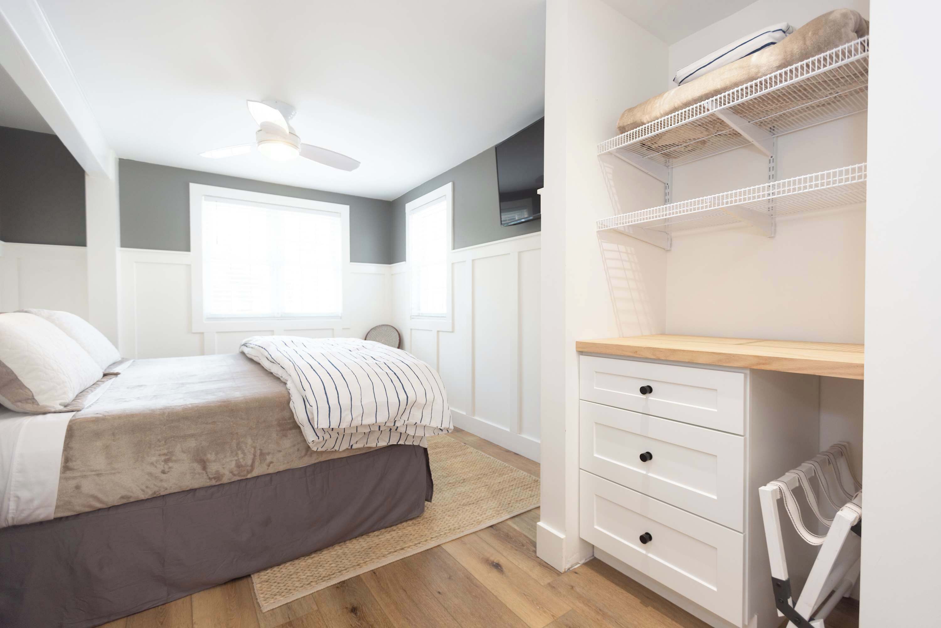 A bedroom with a bed, a desk, and a shelving unit.