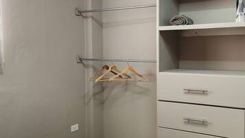 Ein Schlafzimmer mit Bett, Kleiderschrank, Kleiderstange und Klimaanlage.
