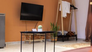 A room with a bed, a TV mounted on the wall, a small table, and a potted plant. - Atomium Apartments (Tirana)