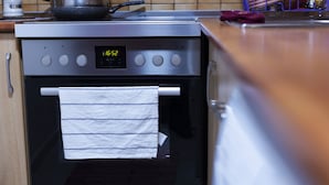 A kitchen with a stainless steel oven, a digital clock displaying 16:02, and a wooden countertop. - Atomium Apartments (Tirana)