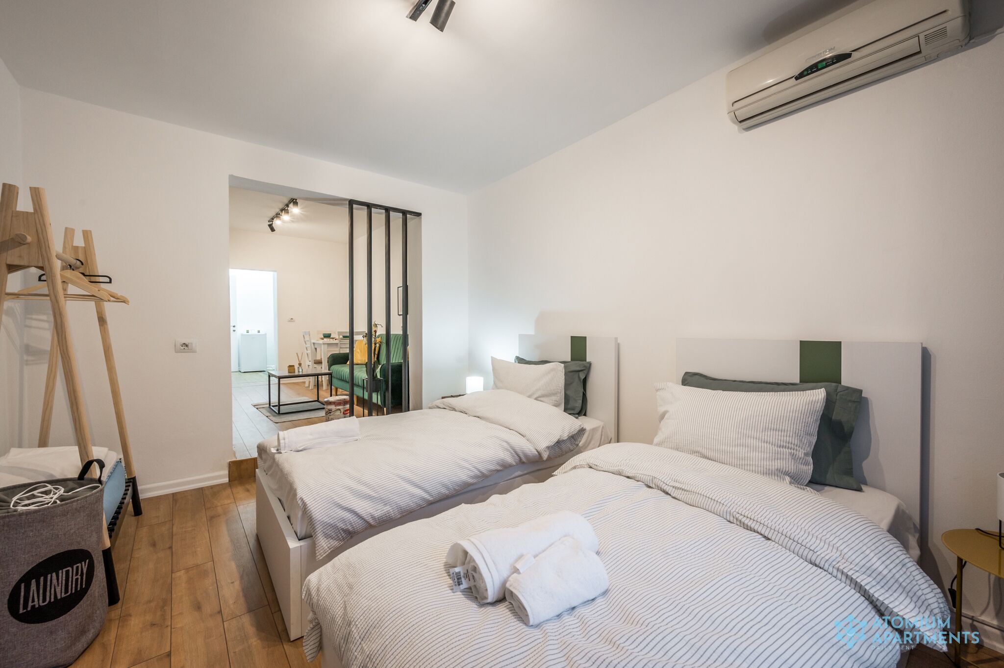 A hotel room with two beds, a laundry basket, and an air conditioning unit.