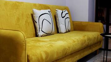 Un canapé jaune agrémenté de deux coussins blancs ornés de motifs abstraits noirs.