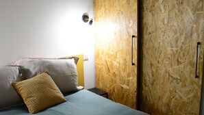 A bed with a teal bedspread and two pillows, a wooden headboard, and a wall-mounted light fixture. - Proche DU Vieux Port AU Calme (Marseille)