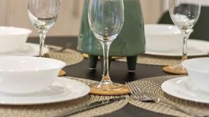 A dining table with three wine glasses, plates, and a green potted plant.