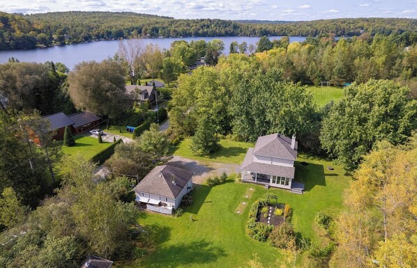 A residential area with two houses, a lake, and a forested landscape.