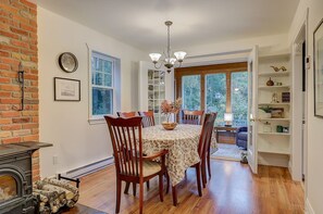 A dining area with a table set for four, a brick wall, a fireplace, and a view through a window.
