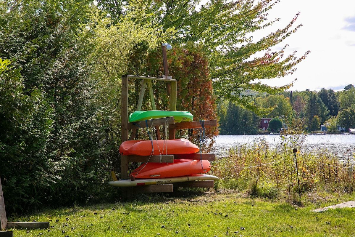 Eine Holzkonstruktion mit Kajaks und einem Stand-Up-Paddleboard am See.