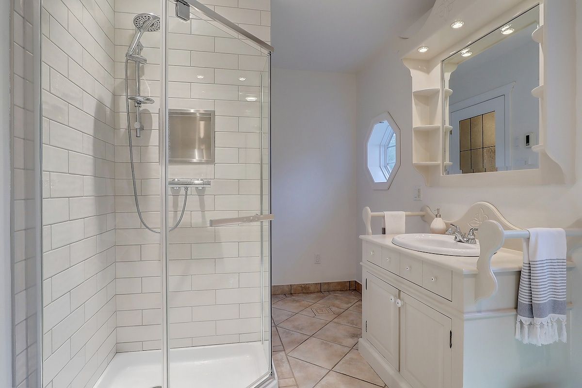 A modern bathroom with a glass-enclosed shower, a vanity with a sink, and a mirror above the vanity.