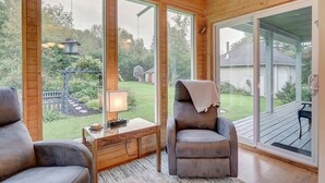 Ein gemütliches Zimmer mit großen Fenstern, einer Holzbalkendecke und Blick auf einen Hinterhof.