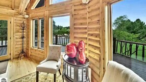 A wooden cabin with a balcony, large windows, and a view of the outdoors.