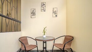 A corner balcony with two wicker chairs and a small table with a potted plant. There are three framed artworks on the wall. - Hermoso y Tranquilo Loft con Netflix Incluido (Lima)