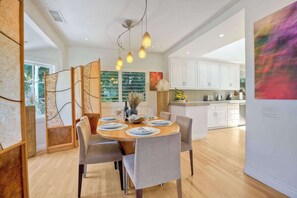 A dining area with a round table, chairs, and hanging pendant lights.