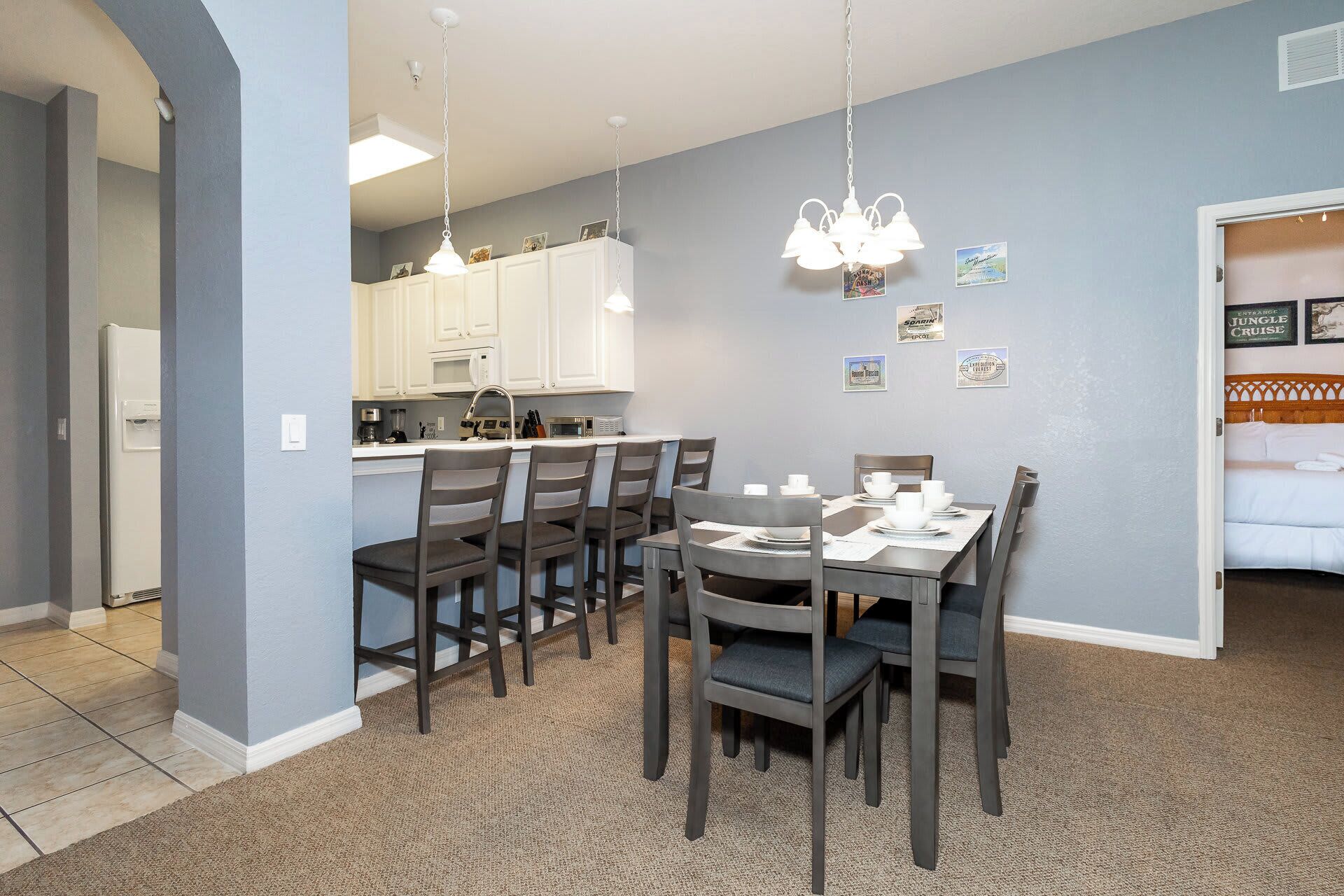 A modern kitchen with white cabinets, a dining area with a table and chairs, and a living area with a sofa and a coffee table.