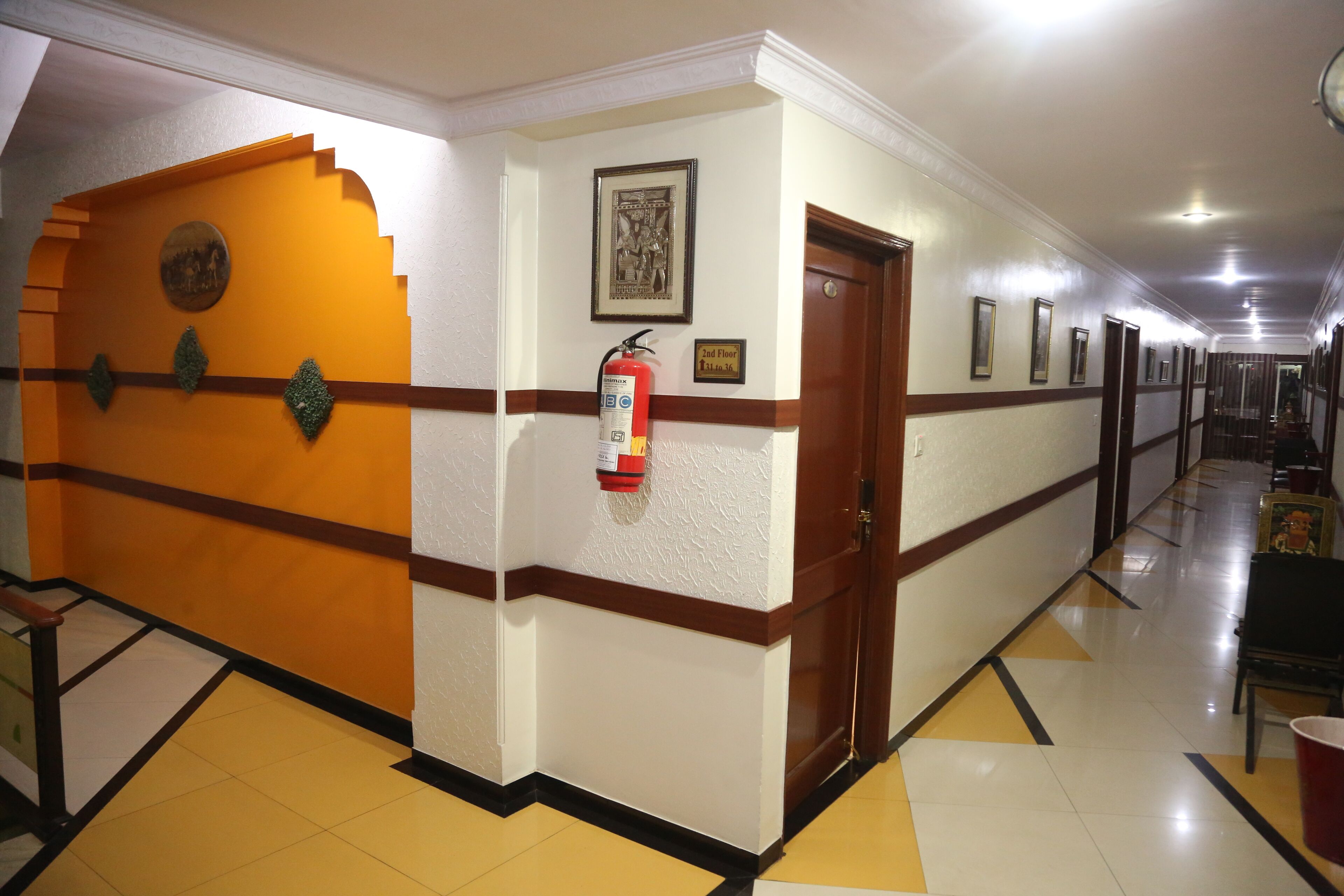 A hotel corridor with a fire extinguisher, a door marked "2nd Floor," and a framed picture on the wall.