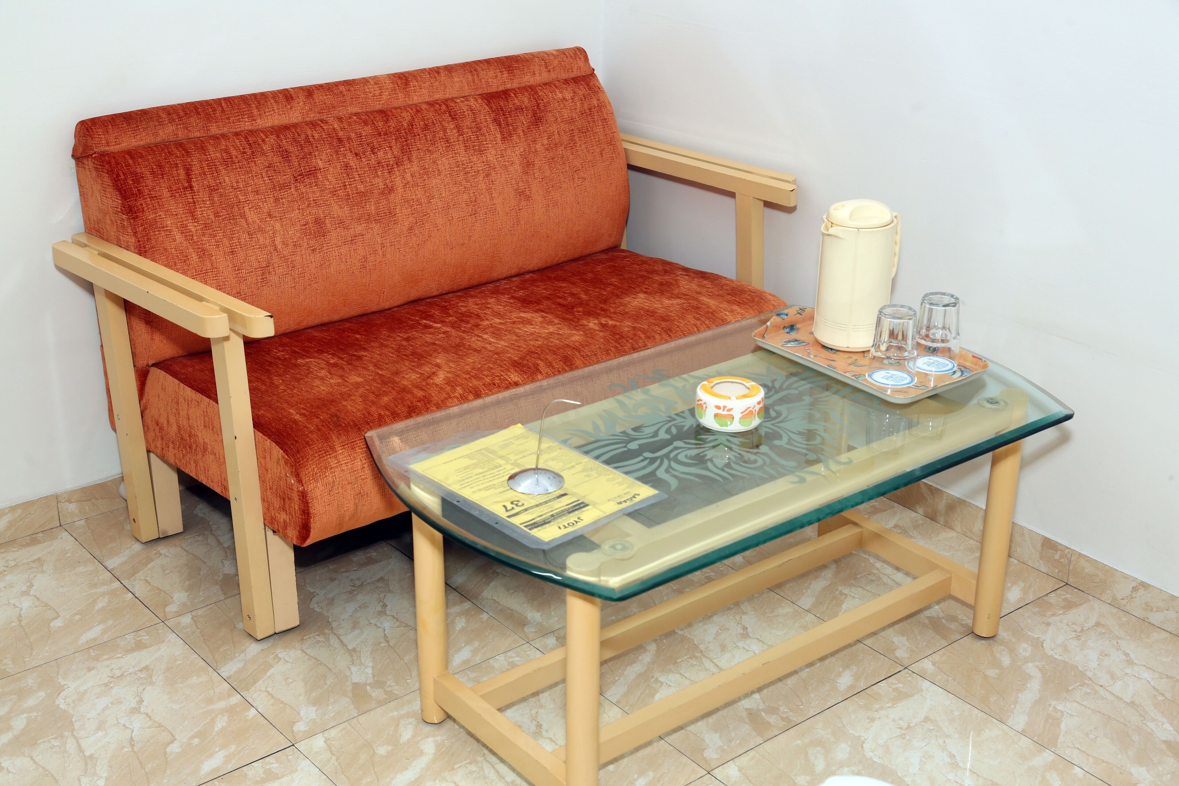 A small room with a sofa and a glass-top table with a tray.