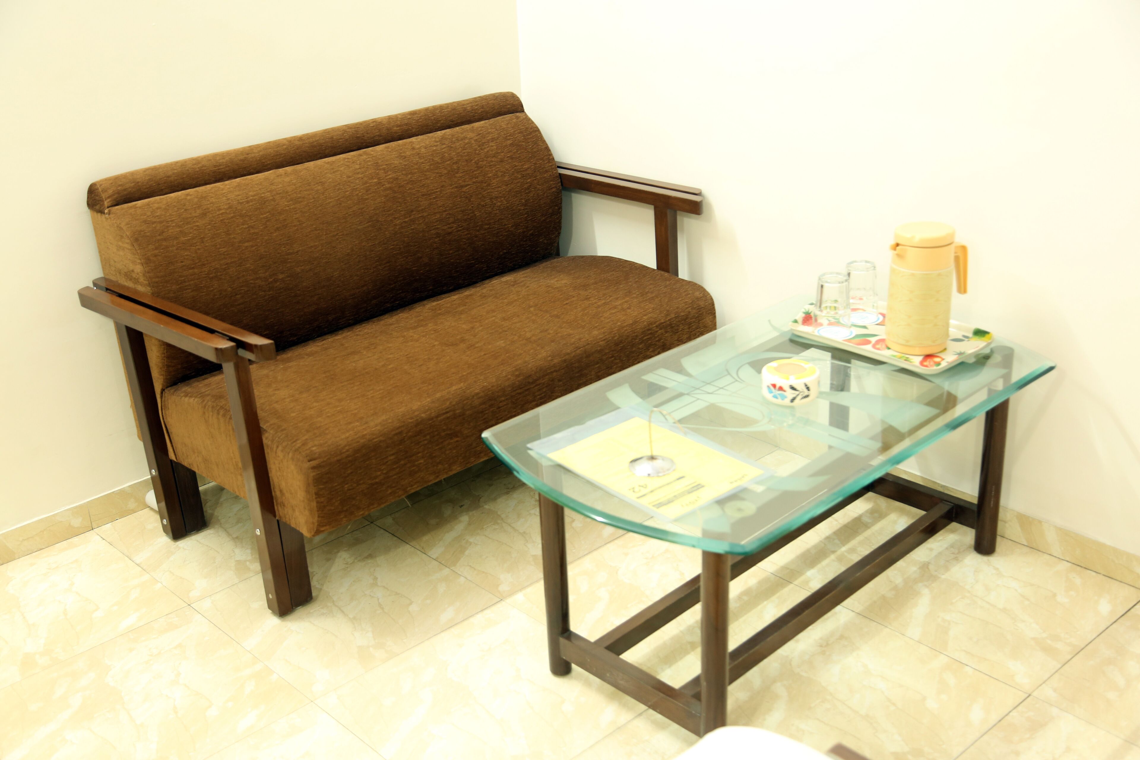 A brown sofa and a glass-top table with a yellow mug and glasses.
