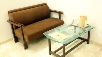 A brown sofa and a glass-top table with a yellow mug and glasses.